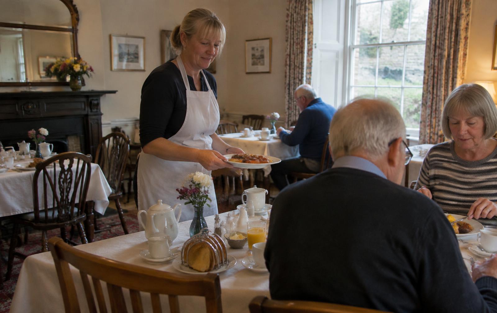 The owner of a small guest house serving breakfast to guests